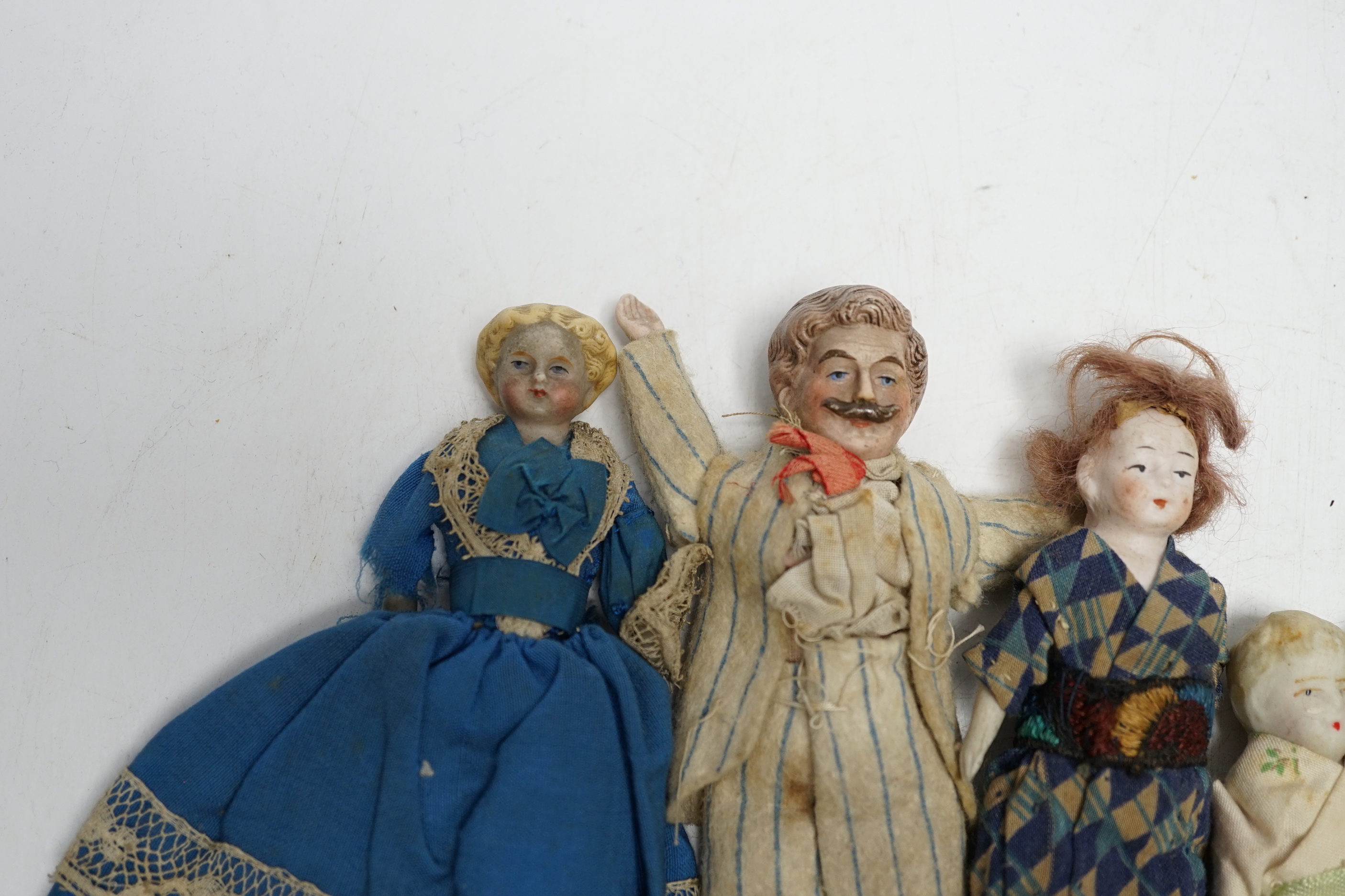 Six doll's house dolls, two c.1860 and a male figure with moustache, two other bisque later figures and one small doll, damaged